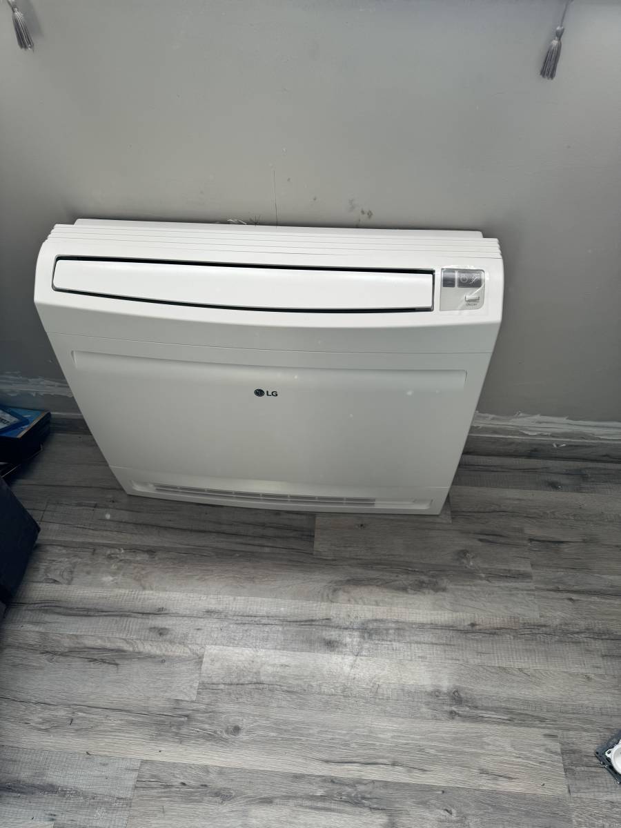 Pose d’une unité murale de PAC air/air dans un salon à Gonfreville-l’Orcher