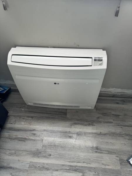 Pose d’une unité murale de PAC air/air dans un salon à Gonfreville-l’Orcher